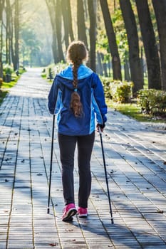 Nordic walking adventure and exercising concept - woman hiking withnordic walking poles in park