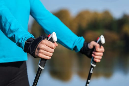 Nordic walking exercise adventure hiking concept - closeup of woman's hand holding nordic walking poles