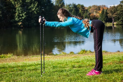Nordic walking adventure and exercising concept - woman doing exercise with nordic walking poles in park