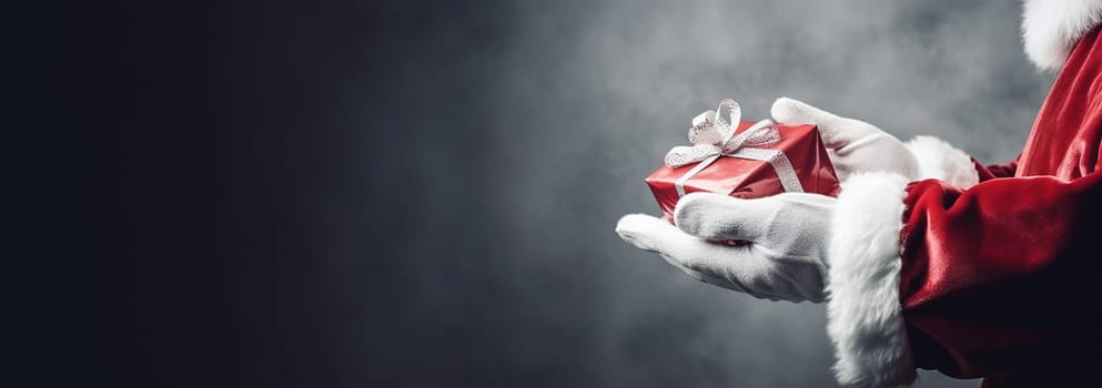 Christmas concept. Close up photo of Santa Claus hand holding a gift. Happy New Year, Merry Christmas, Celebration concept Sparkling present box with copy space space for text