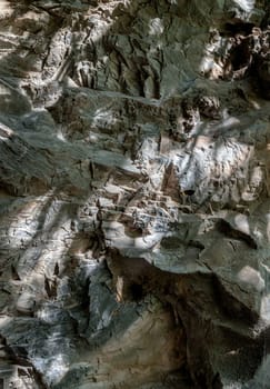 Elegance of The intricate natural light and shadow on surface of stone wall. Pattern of granite on the mountains that erode naturally, The sunlight shining through down to Limestone walls on the outside cave walls, use it as your Wallpaper, Poster and Copy space, Selective focus.