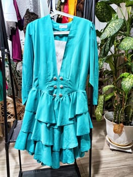 Stylish turquoise dress at a second-hand sale showcases eco-friendly shopping at a private residence.