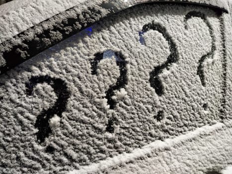 Frost-covered car window displays several question marks, symbolizing insecurity and uncertainty in a business context during winter.