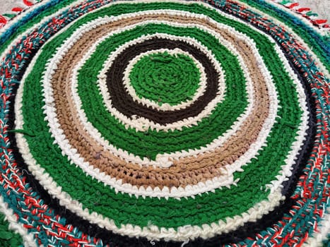 This circular textile features intricate patterns in shades of green, brown, and white, showcasing exceptional craftsmanship and design.
