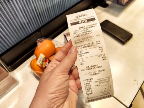 Osaka, Japan - October 26, 2024: Receipt shows a list of items purchased at a convenience store in Osaka, Japan, including fruits and snacks bought during the visit.