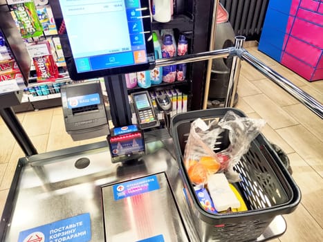 Kirov, Russia - December 11, 2024: A self-service checkout station displays a basket filled with groceries, including fruits and other essentials, in a retail environment.