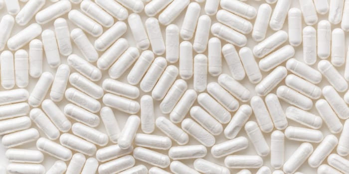 Scattered white medicine, pills or capsules on white table. Mock up background from top view. Medical, pharmacy and healthcare. High-quality photo mock-up banner. Healthy Bio Supplements. Pharmacology