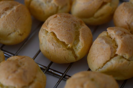 Freshly baked golden pastry puffs sit on a rack, exuding warmth and inviting aromas in a charming kitchen.