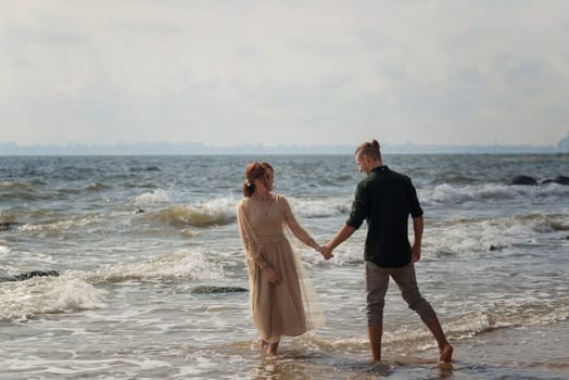 lovers and romantic newlyweds having fun on the seashore. couple running on the water. on a bright sunny day lovers dancing on the sea. girl wearing a beige dress. they barefoot in the sea