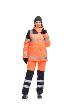 Woman in orange working trousers and jacket with reflective strips and knitted cap isolated full-length view