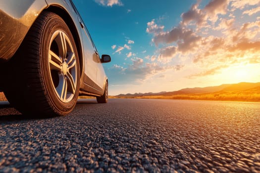 A striking close-up of a car tire on a smooth asphalt road during a breathtaking sunset. The vibrant sky contrasts beautifully with the serene landscape, conveying a sense of adventure.