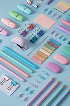 Stationery background with pastel-colored office supplies neatly arranged on a light blue background. Selective focus.