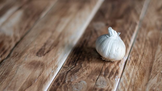 one head of garlic on wooden planks background, horizontal photo with shallow depth of field, minimalism, copy space,