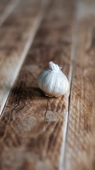 one head of garlic on a background of wooden boards, vertical photo with shallow depth of field, Minimalism, copy space,