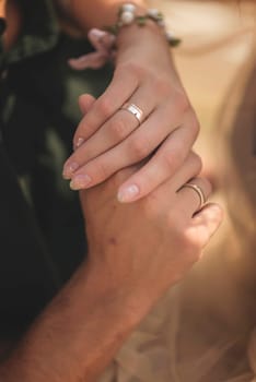 wedding rings at a wedding and hands close-up. bride's hand and groom's hand. photo has a vertical orientation. gold rings on elegant hands