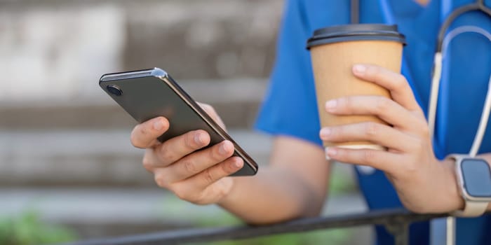 A nurse taking a break, holding a coffee and checking her smartphone, balancing work and relaxation in a modern medical environment.