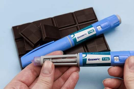 Insulin injection pen and dark chocolate for diabetics and weight loss. Copenhagen, Denmark - January 25, 2025