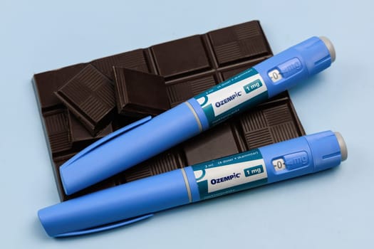 Insulin injection pen and dark chocolate for diabetics and weight loss. Copenhagen, Denmark - January 25, 2025