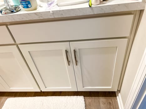 Castle Rock, Colorado, USA-March 29, 2023-Modern kitchen featuring white cabinets with silver handles, granite countertops, and a hexagon tile backsplash. Countertop appliances include an air fryer and toaster, with a knife block and cutting board for added functionality. Light wood flooring completes the contemporary design.