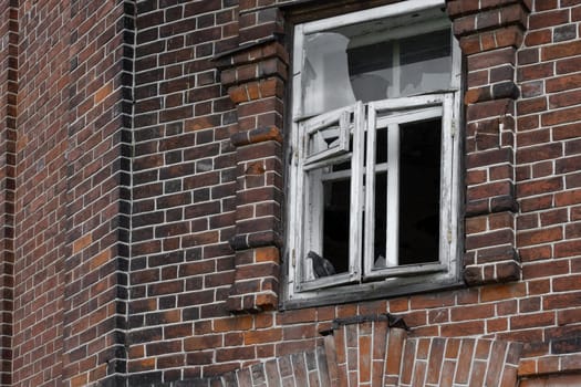 A fragment of a brick wall and a broken window of an old abandoned house. Selective focus.