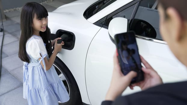 Progressive lifestyle of mother and daughter who have just returned from school in an electric vehicle that is being charged at home. Electric vehicle powered by sustainable clean energy.