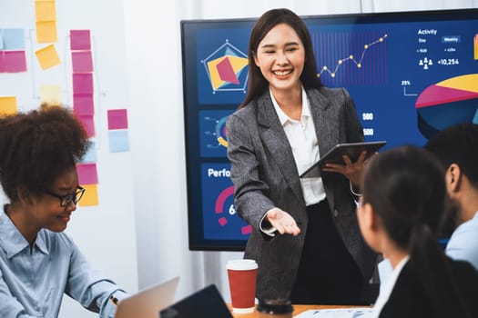 Young asian businesswoman presenting data analysis dashboard on TV screen in modern meeting. Business presentation with group of business people in conference room. Concord