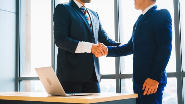 Business people handshake in corporate office showing professional agreement on a financial deal contract. Jivy