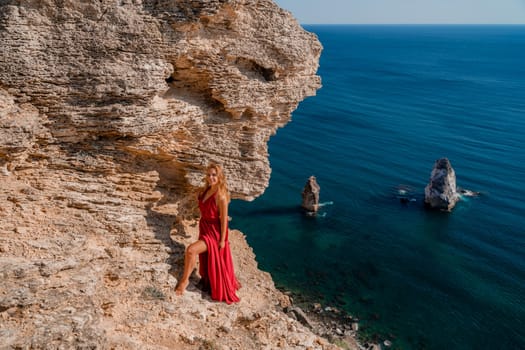 A woman in a red flying dress fluttering in the wind, against the backdrop of the sea