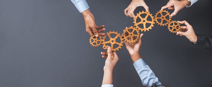 Panoramic shot top view of business people holding cog wheel as unity and teamwork in corporate workplace concept. Office worker colleague with symbol of visionary system for business success. Concord