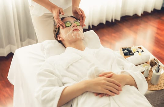 Serene daylight ambiance of spa salon, woman customer indulges in rejuvenating with luxurious cucumber facial mask. Facial skincare treatment and beauty care concept. Quiescent