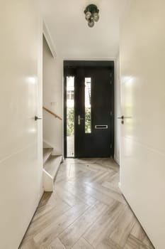 an entry way with wood flooring and black front door leading to the entranceway on the left is a white wall