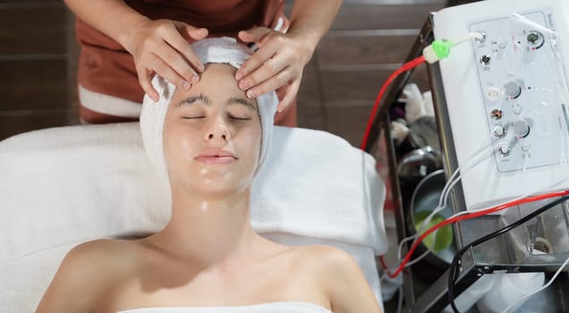 Beautiful young women with beautiful skin having facial massage surrounded by professional therapist using beauty electrical equipment. Top view. Healthy and beauty concept. Tranquility.
