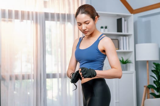 Fit young asian woman portrait in sportswear preparing herself before healthy exercising routine at home. Domestic fitness workout training on living room. Vigorous