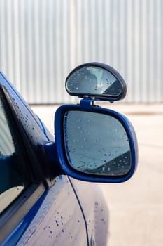 Car side mirror with water droplets close up