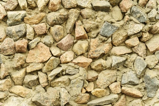 Old rough stone wall made of various square natural stones in beige, gray and brown colors. Construction texture.