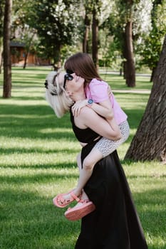 Girl hugging mother in spring or summer park. Family relaxing outdoors. Mothers day. Close up.