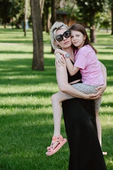 Girl hugging mother in spring or summer park. Family relaxing outdoors. Mothers day. Close up.