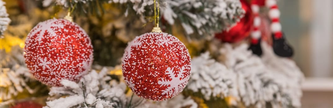 Banner with golden Christmas tree ornament, hanging from fir tree branch with silver tree baubles