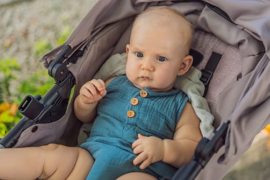 A cute baby, dressed in soft muslin clothes, sits contentedly in a stroller, basking in comfort and coziness on a sunny day.