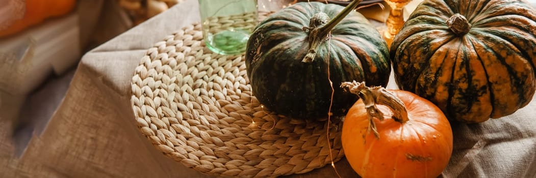 Autumn interior: a table covered with dishes, pumpkins, a relaxed composition of Japanese pampas grass. Interior in the photo Studio. Close - up of a decorated autumn table.