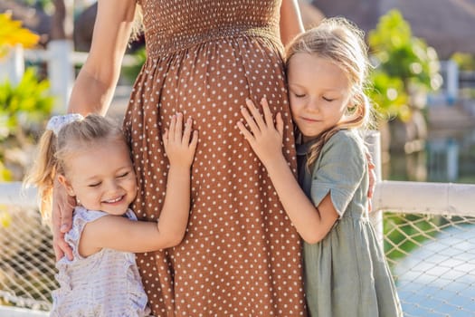 Sisters' love blooms as they tenderly embrace their mother's pregnant belly, sharing anticipation and affection for their soon-to-arrive sibling.