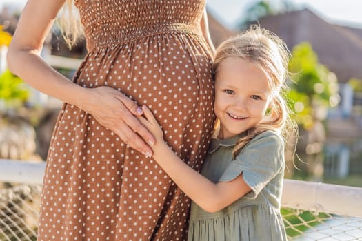 A heartwarming moment captured as a daughter lovingly embraces her mother's pregnant belly, sharing in the excitement and anticipation of a new family member.