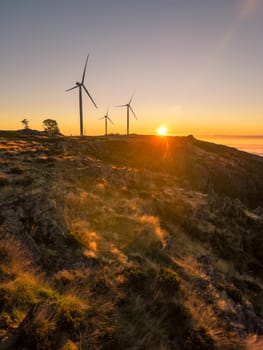 Wind turbines during sunset over a hill in Arouca, Portugal.