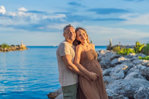 A happy, mature couple over 40, enjoying a leisurely walk on the waterfront On the Sunset, their joy evident as they embrace the journey of pregnancy later in life.