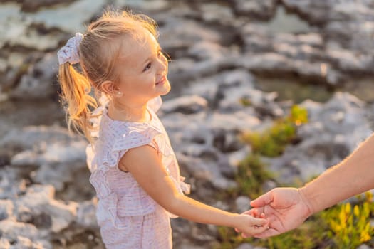 A tiny hand securely nestled in her dad's, a little girl finds comfort and trust in their unbreakable bond, a beautiful moment of parent-child connection.