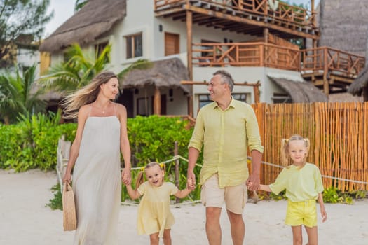 A joyful family, two girls, dad, and a pregnant mom, bask in tropical beach bliss, celebrating a radiant pregnancy amidst paradise.