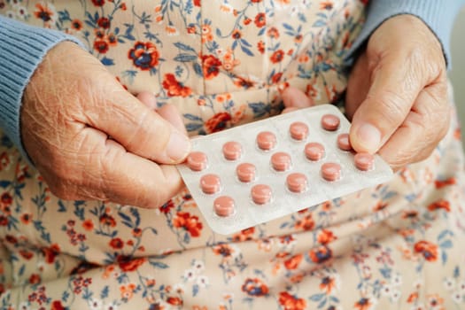 Asian elderly woman holding pill drug in hand, strong healthy medical concept. 