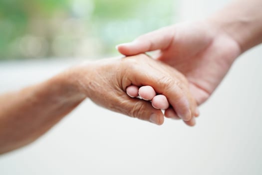 Asian young boy holding old grandmother woman hand together with love and care.