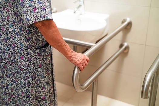 Asian elderly old woman patient use toilet support rail in bathroom, handrail safety grab bar, security in nursing hospital.