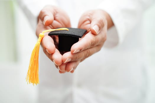 Asian woman doctor holding graduation hat in hospital, Medical education concept.